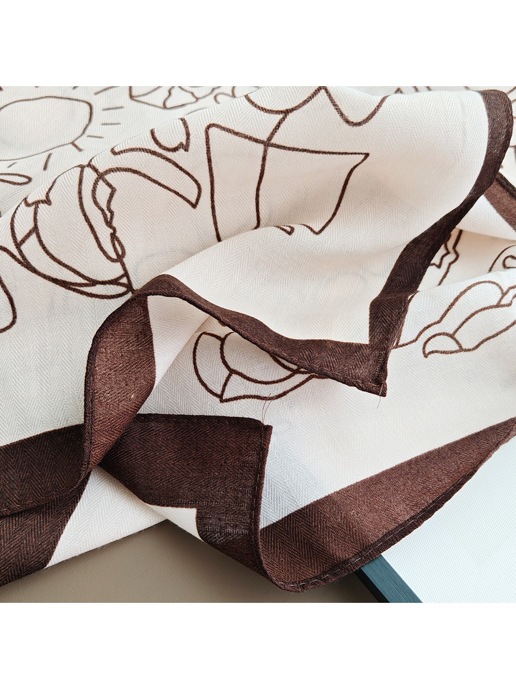 Close-up of the stitched dark brown border and patterned scarf edge