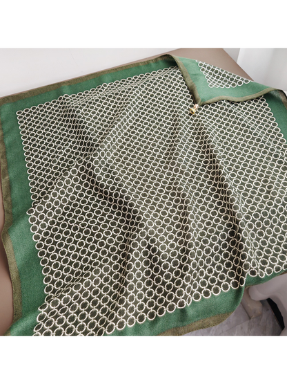 Green square scarf laid open to show the broad border and central ring pattern