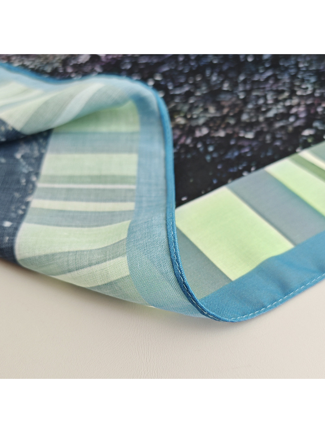 Close-up of the scarf's narrow stitched blue edge and striped border