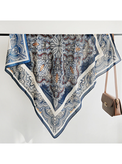 Navy and ivory paisley square scarf draped over a rail beside a handbag