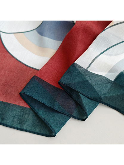 Close-up of the burgundy scarf's dark green border and stitched edge