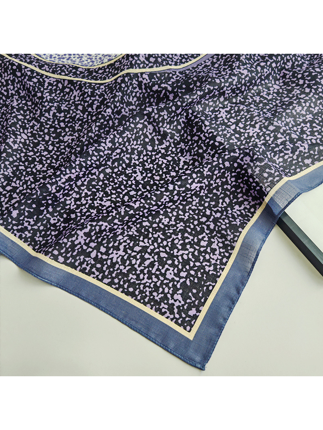 Close-up of the purple speckled print and blue border corner