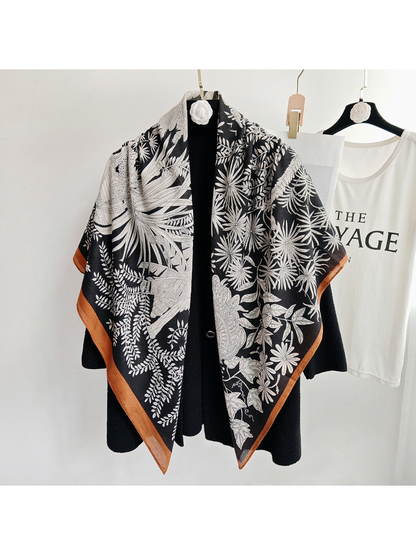 Black botanical square scarf draped over a black coat