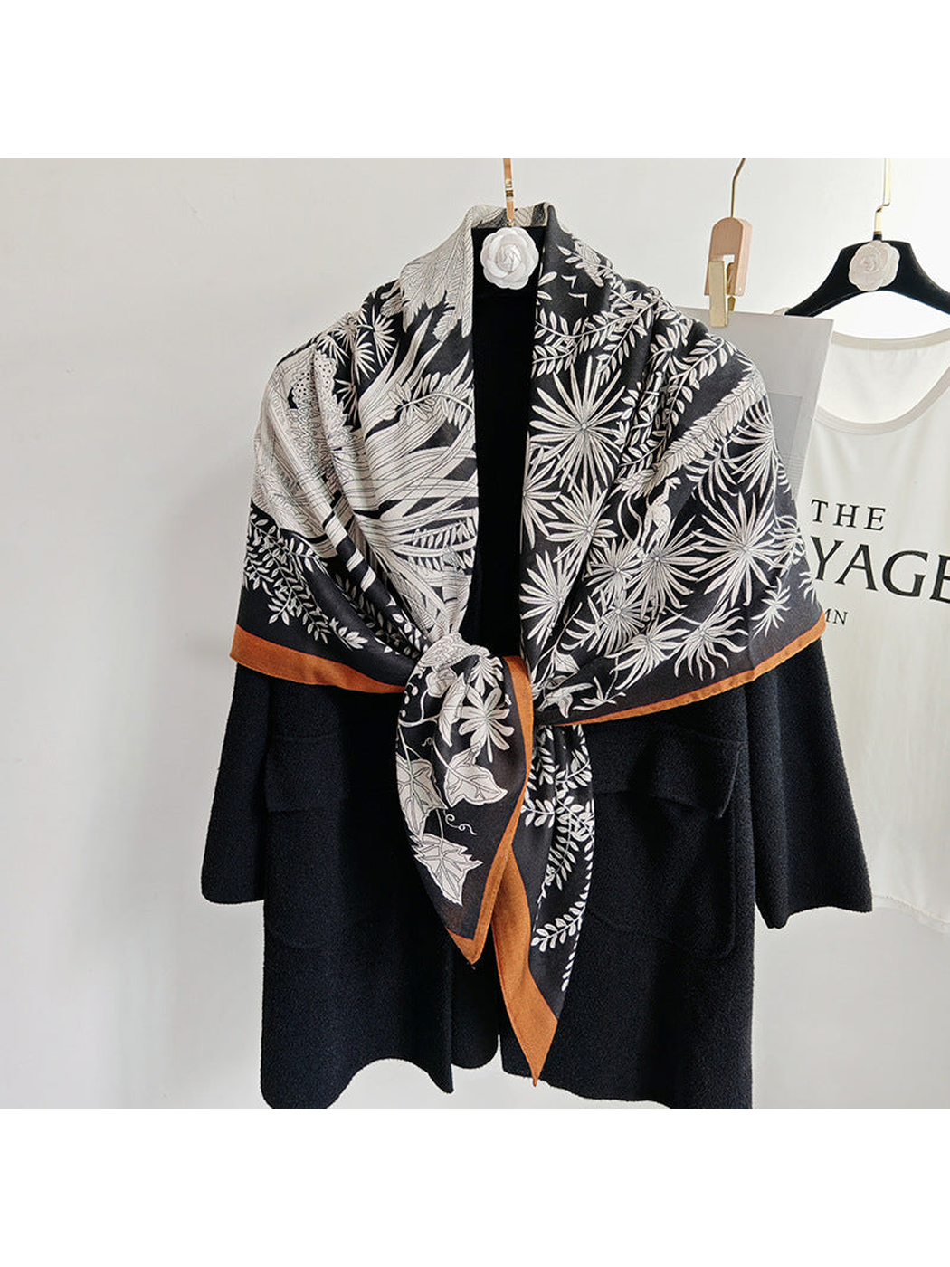 Black botanical square scarf tied over a black coat