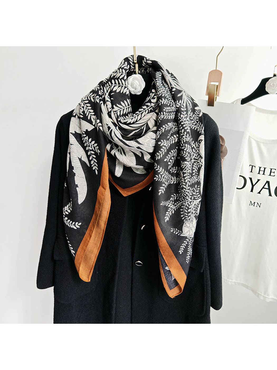 Black botanical square scarf wrapped around the neckline of a black coat