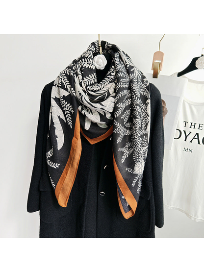 Black botanical square scarf wrapped around the neckline of a black coat
