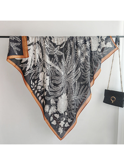Black botanical square scarf fully draped over a display rail