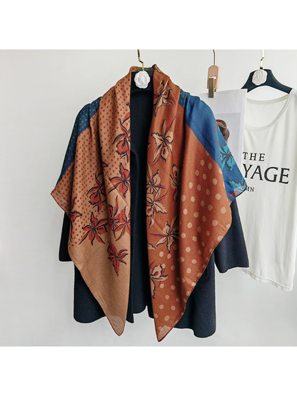 Multicolor floral and polka dot square scarf draped over a black coat