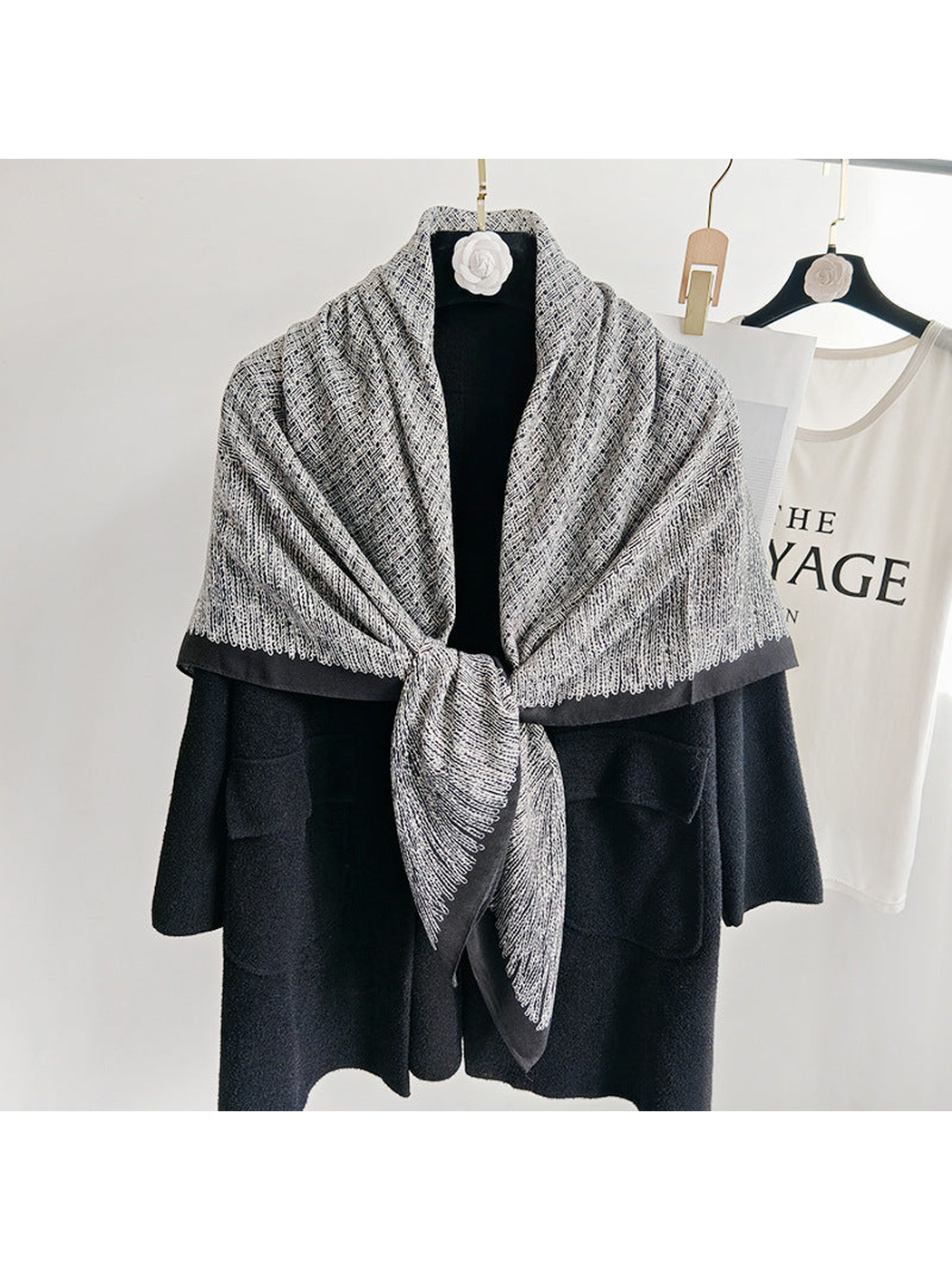 Black and gray patterned scarf tied at the front over a black coat