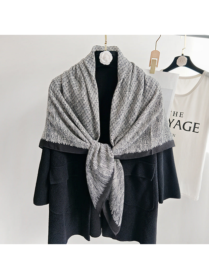 Black and gray patterned scarf tied at the front over a black coat