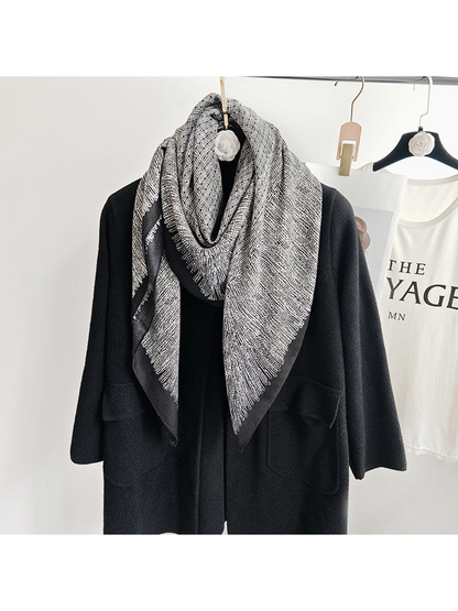 Black and gray patterned scarf looped around the neckline of a black coat