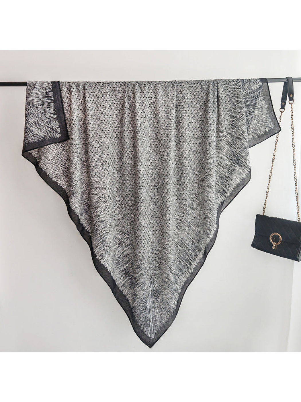 Black and gray square scarf spread over a display rail with pointed drape