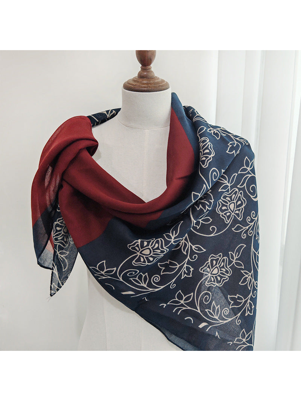 Burgundy and navy floral scarf draped around a display form