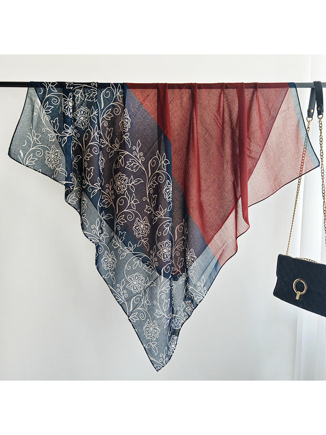 Burgundy and navy floral scarf draped across a display rail