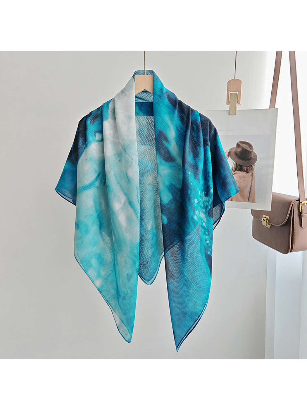 Teal, aqua and navy abstract square scarf displayed open on a hanger