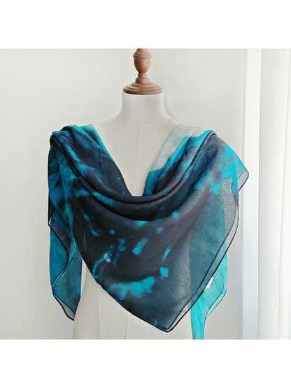 Teal and navy abstract square scarf draped across a dress form