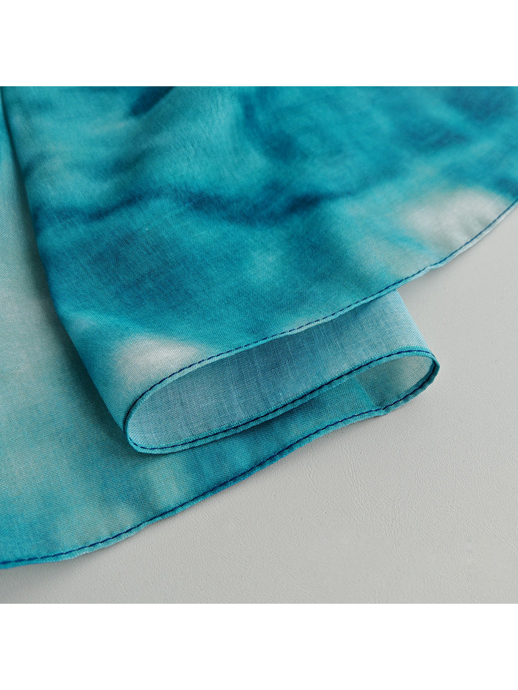 Close-up of the scarf's fine semi-sheer surface and narrow stitched edge