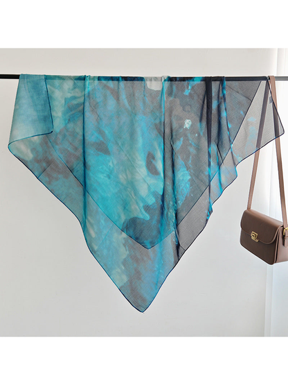 Teal and navy abstract square scarf draped over a display rail
