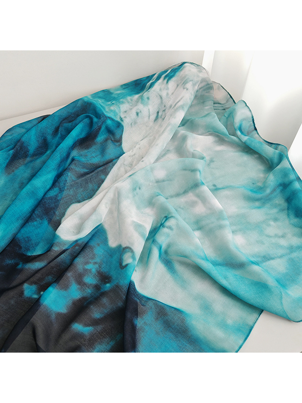 Close-up of the scarf's flowing aqua, white, teal and navy color transitions