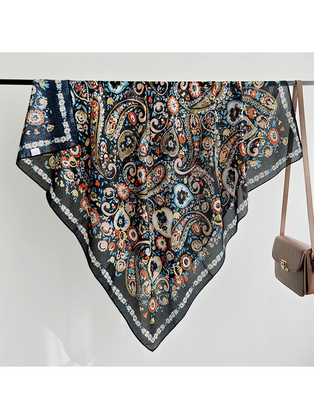 Black paisley and floral square scarf draped over a rail