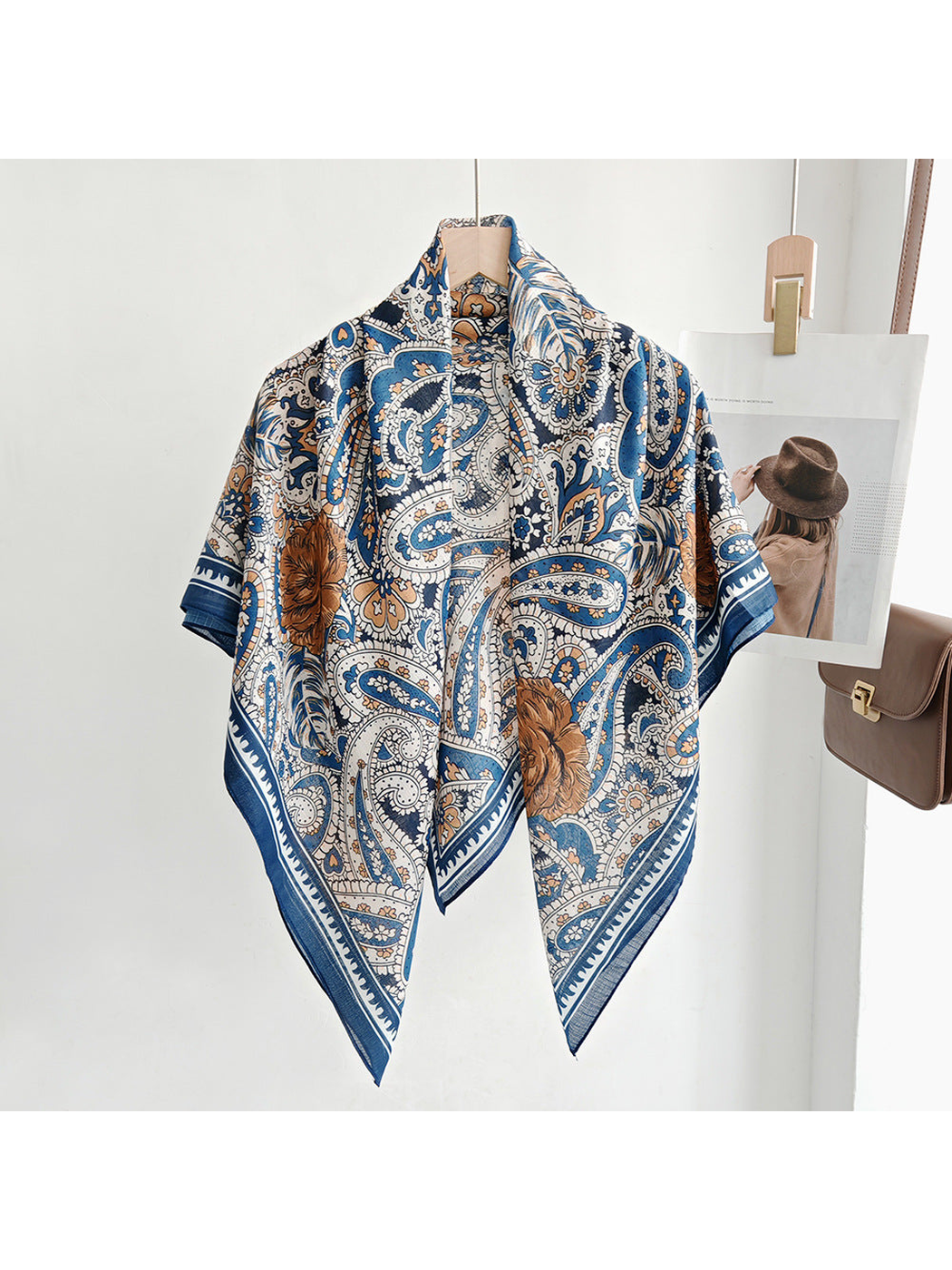 Blue, cream and brown paisley square scarf draped over a hanger