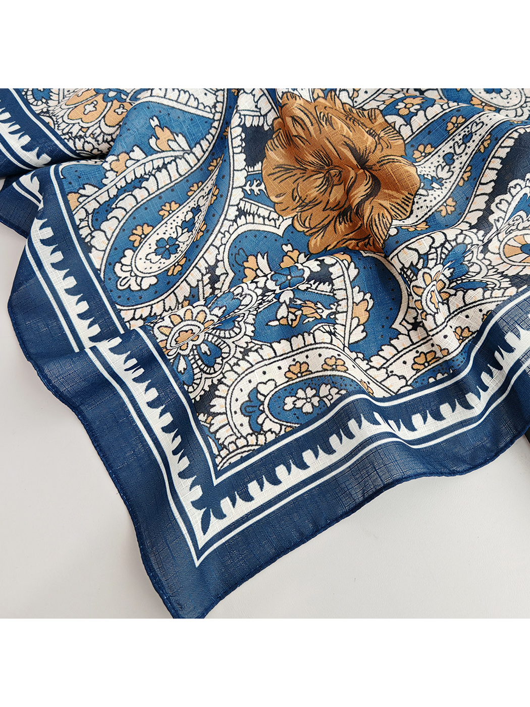 Close-up of the paisley print, brown floral motif and dark blue corner border