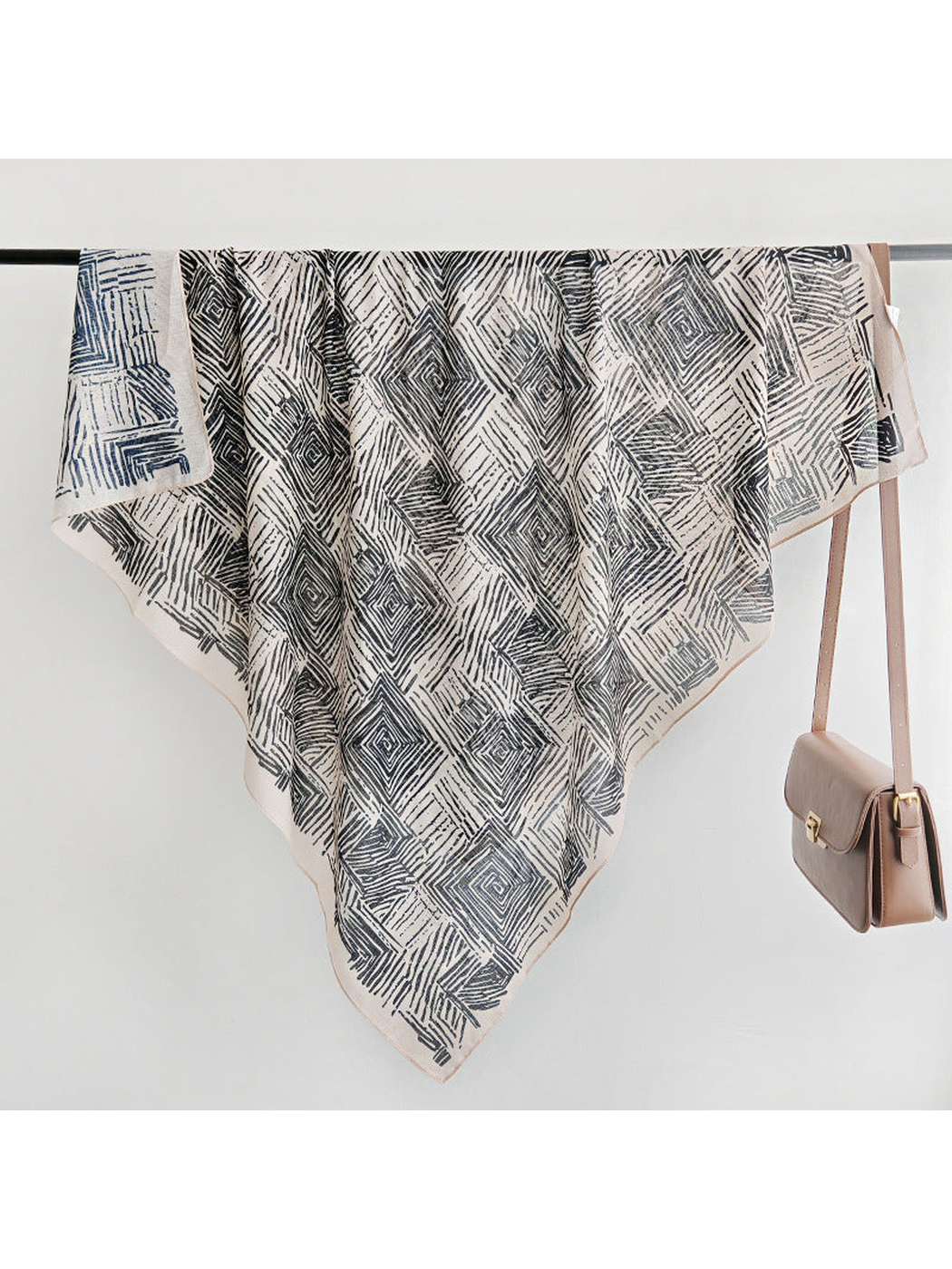 Black and beige geometric square scarf displayed over a rail