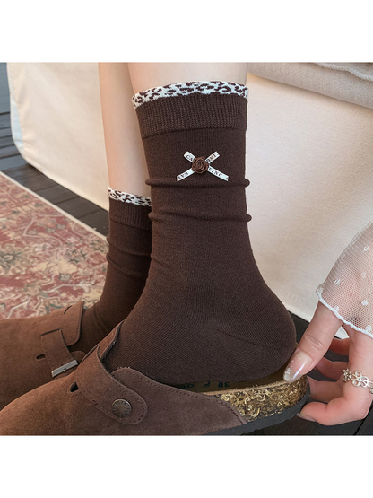 Dark brown crew socks with ribbon rose accents worn with brown clogs