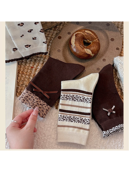 Three brown and ivory crew sock styles showing leopard patterns and bow details