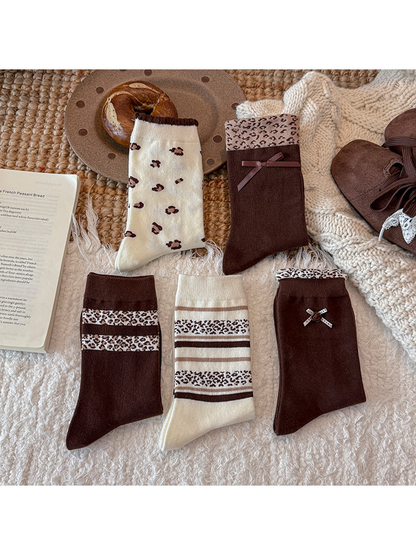 Five brown and ivory crew sock styles displayed separately in a flat lay