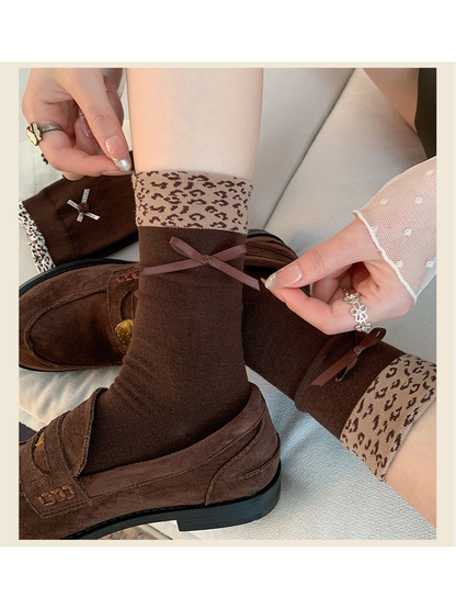 Dark brown crew socks with leopard cuffs and ribbon bows worn with loafers