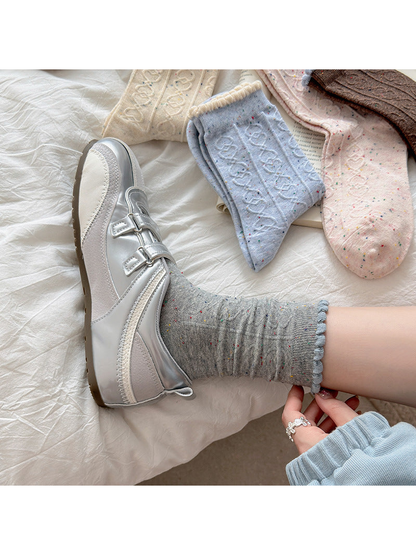 Gray flecked crew sock styled with a silver-tone shoe beside other colors
