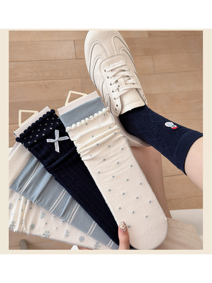 Navy Snowman crew sock worn with a cream sneaker beside the five sock styles