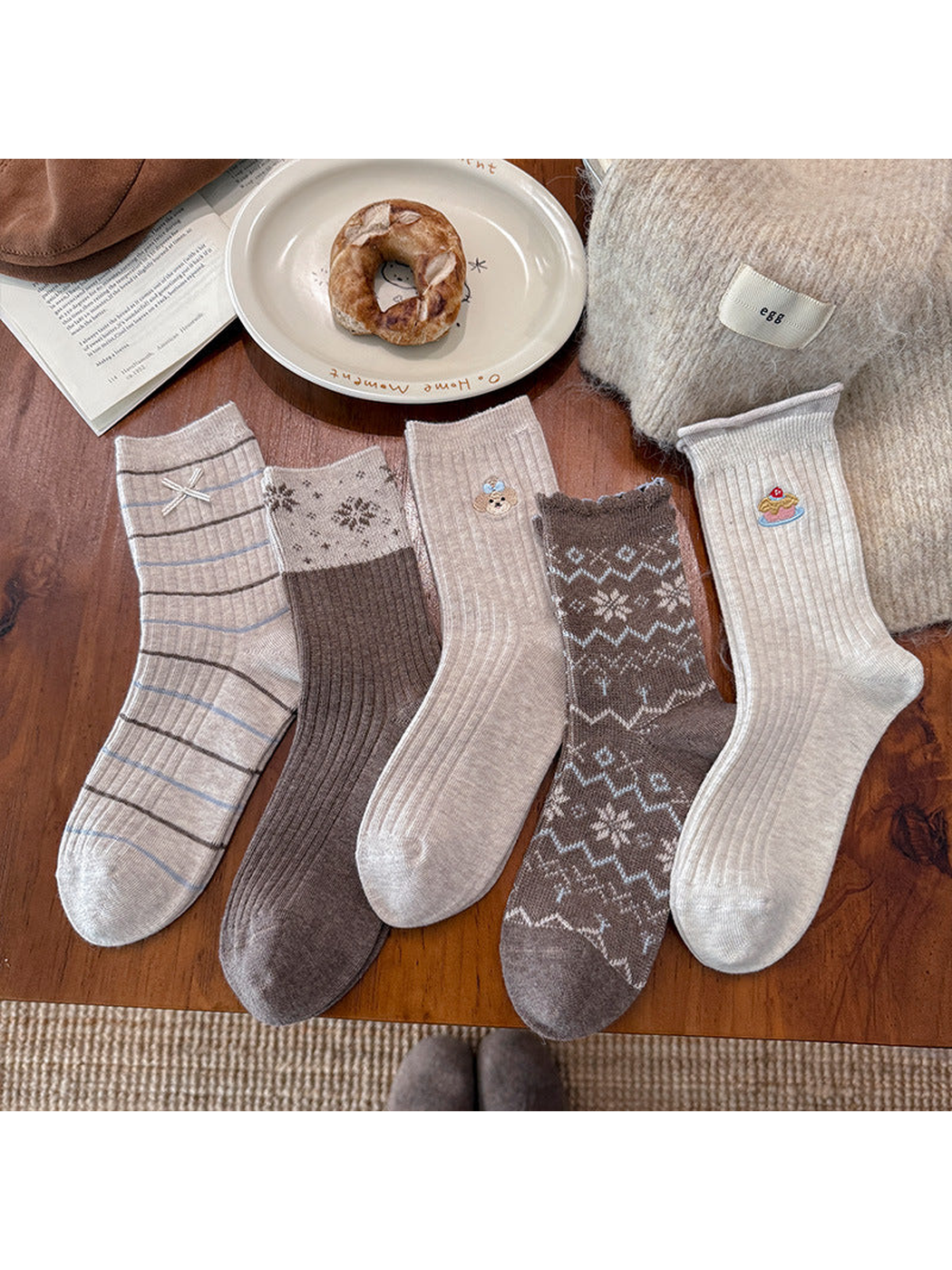 Five neutral crew sock styles arranged on a wooden table
