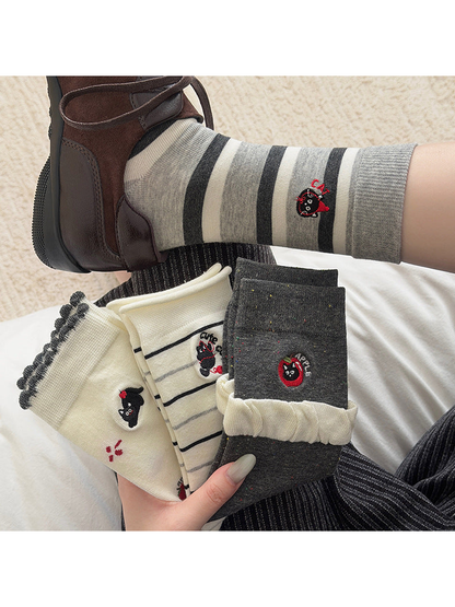 Apple Cat crew socks worn with brown sneakers beside the four sock styles