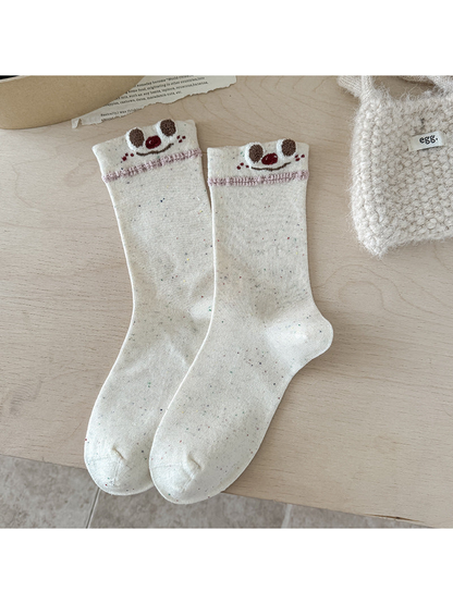 Smiley beige crew socks with speckled pattern and embroidered cuff faces