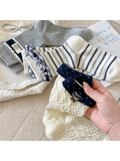 Close-up of striped ruffle, pom-pom, and geometric sock details