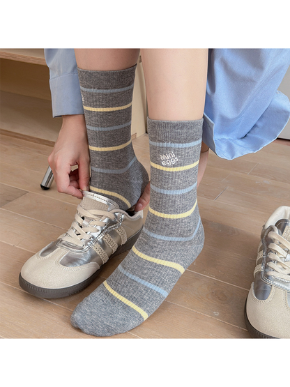Lettered Stripes gray crew socks worn with silver-tone sneakers