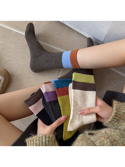 Five color-block sock styles held beside a Dark Brown sock worn on foot