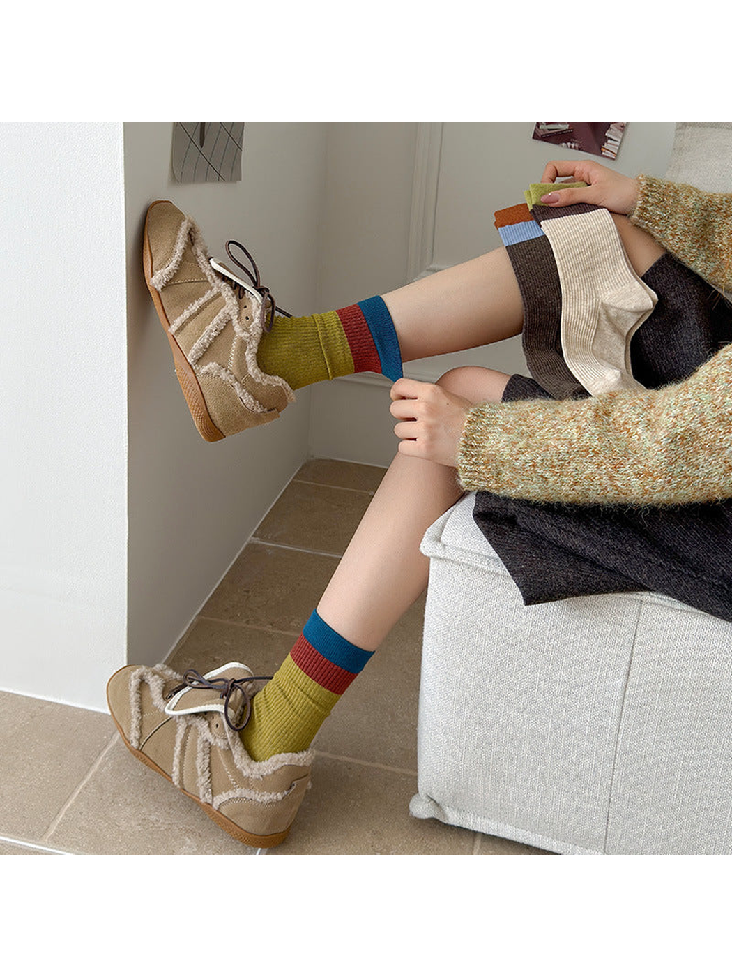Army Green color-block socks worn with beige shoes while additional colors are held
