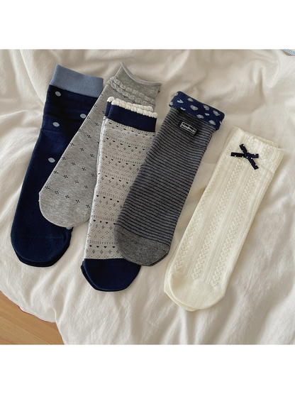 Five crew sock colors and patterns laid out together on ivory fabric