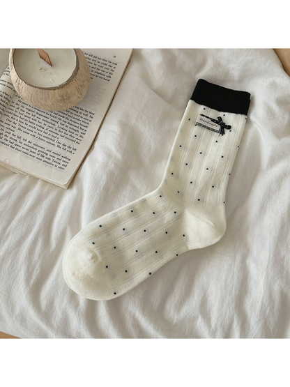 Ivory polka-dot crew sock with black cuff and bow accent