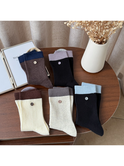 Five color-block ribbed crew sock styles arranged on a table