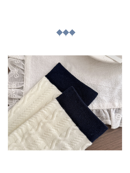 Close-up of ivory cable-knit crew sock cuffs with navy ribbed trim