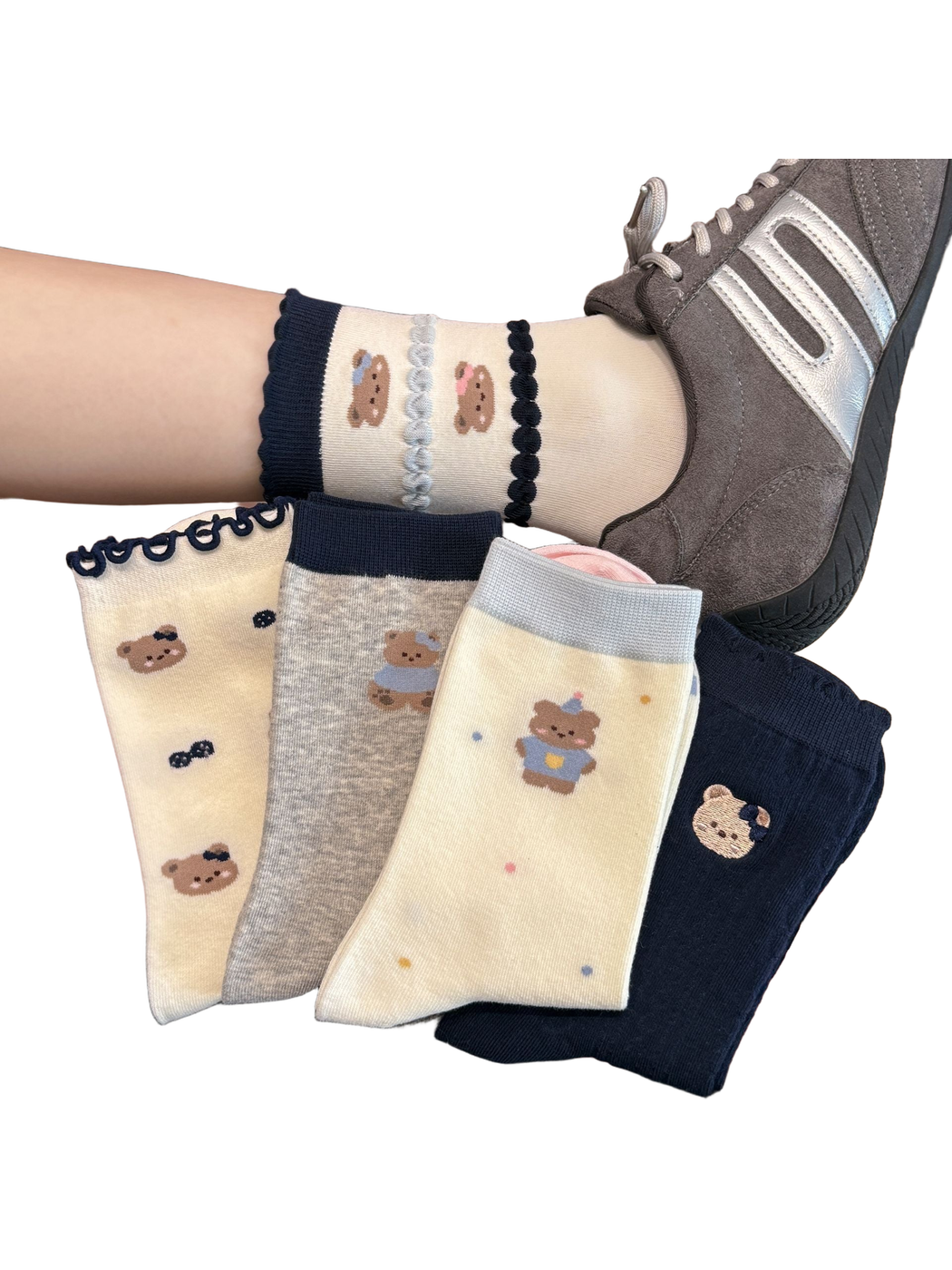 Assorted bear-pattern crew socks displayed by hand and worn with a gray sneaker