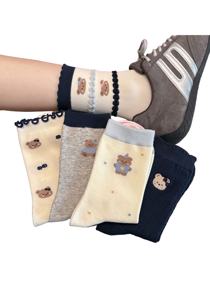 Assorted bear-pattern crew socks displayed by hand and worn with a gray sneaker