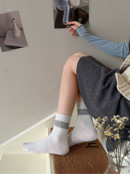 White crew socks with gray dotted ankle bands worn on indoor steps