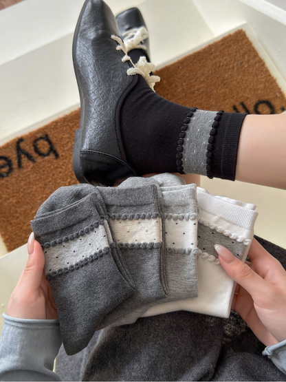 Five neutral color styles of crew socks displayed together with one Black sock worn
