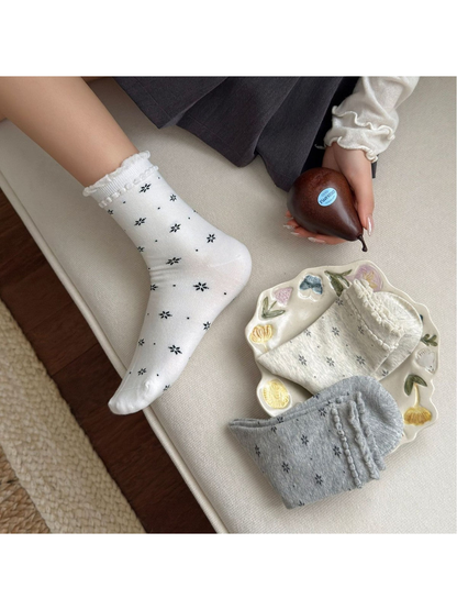 White floral crew sock worn in a seated side view with gray color options nearby