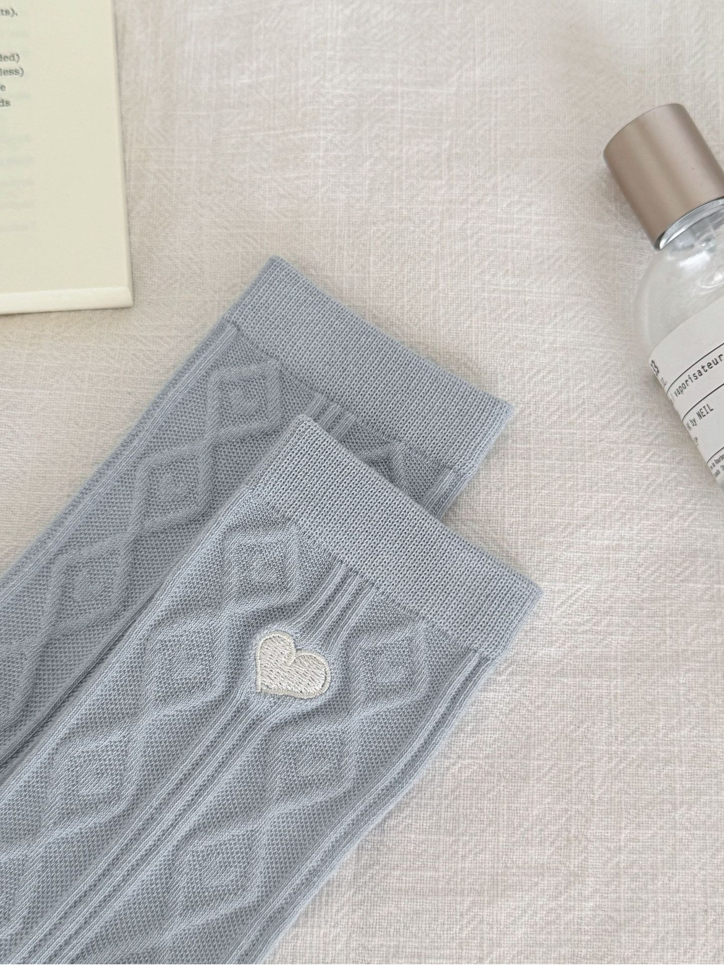 Close-up of the light blue ribbed cuffs, diamond knit pattern and embroidered heart